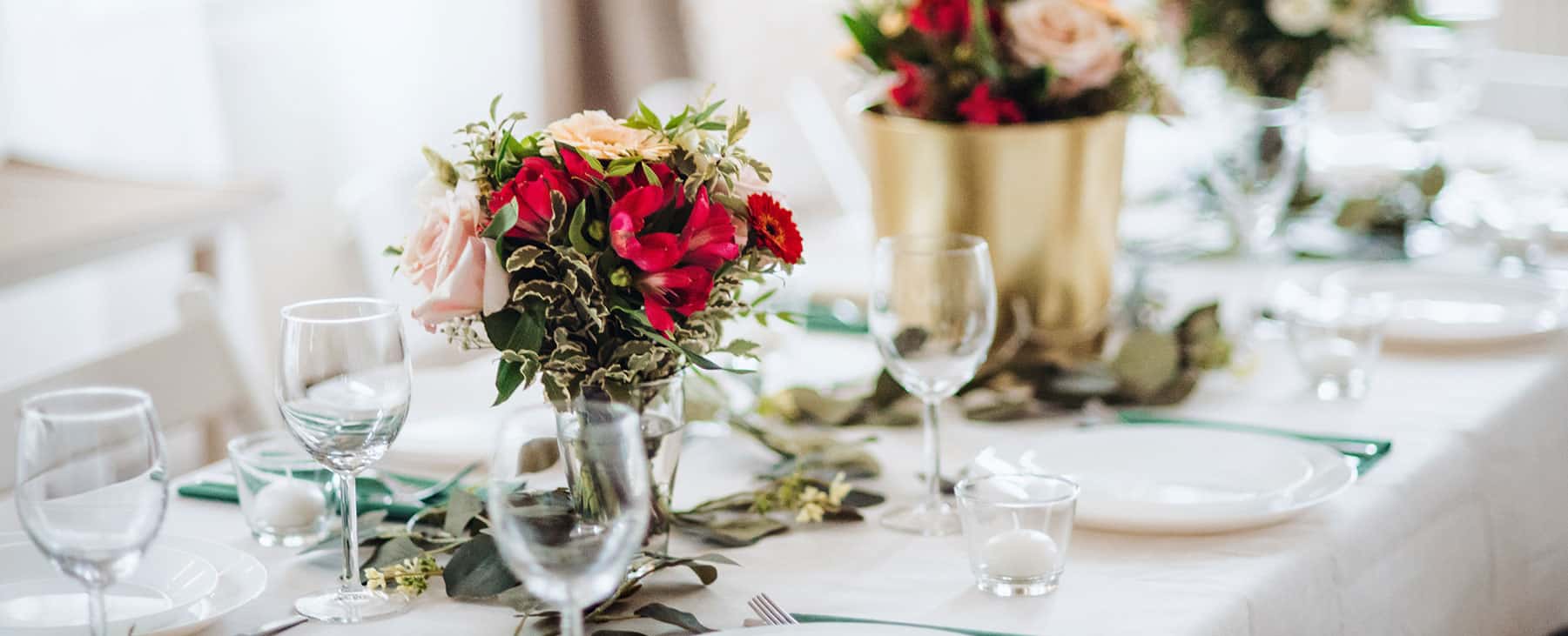 Festlich gedeckte Tafel mit rotem und weißem Blumenschmuck